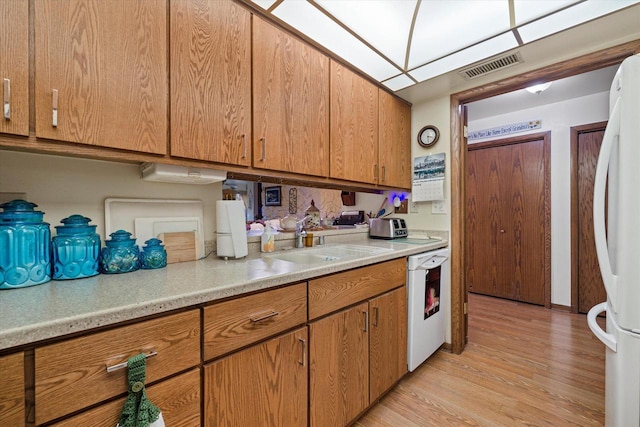 kitchen with sink, white appliances, and light wood-type flooring