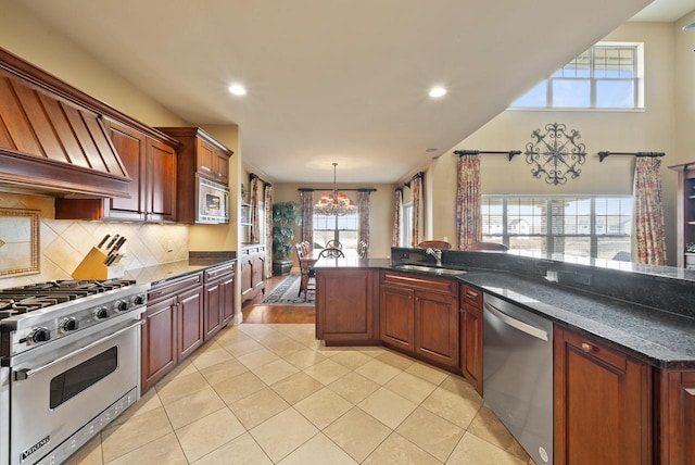 kitchen featuring light tile patterned flooring, appliances with stainless steel finishes, tasteful backsplash, sink, and hanging light fixtures