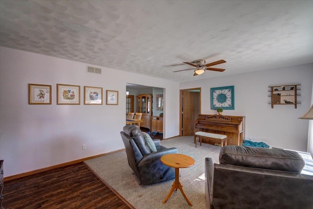 living room with hardwood / wood-style flooring, ceiling fan, and a textured ceiling