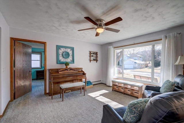 sitting room with a baseboard radiator, light colored carpet, ceiling fan, and a textured ceiling