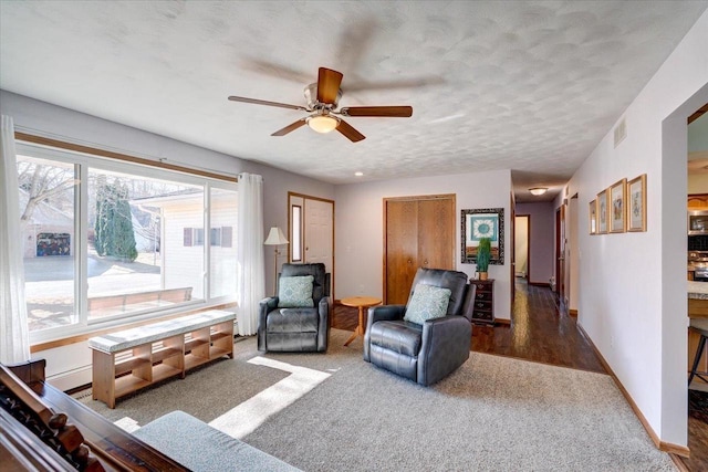 carpeted living room with ceiling fan and a textured ceiling