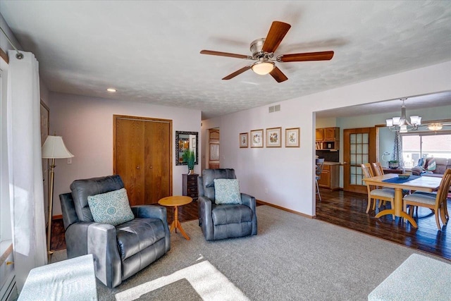 living room with baseboard heating, ceiling fan with notable chandelier, and a textured ceiling