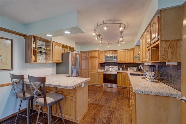 kitchen featuring sink, dark hardwood / wood-style floors, a kitchen breakfast bar, kitchen peninsula, and stainless steel appliances