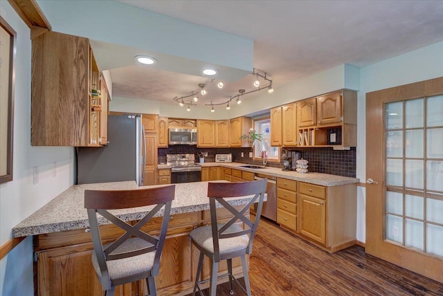 kitchen with sink, dark wood-type flooring, a breakfast bar, stainless steel appliances, and decorative backsplash