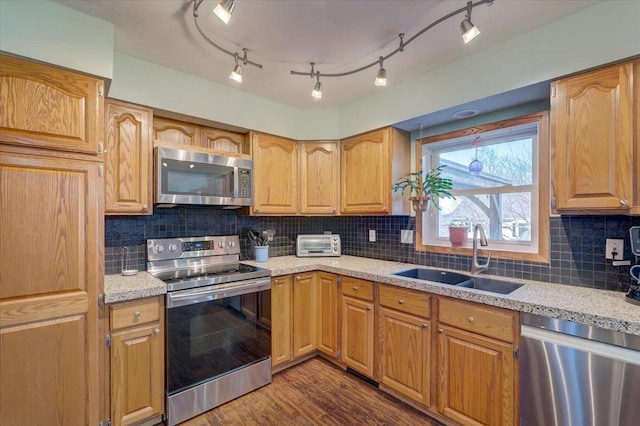 kitchen with appliances with stainless steel finishes, dark hardwood / wood-style floors, sink, and backsplash