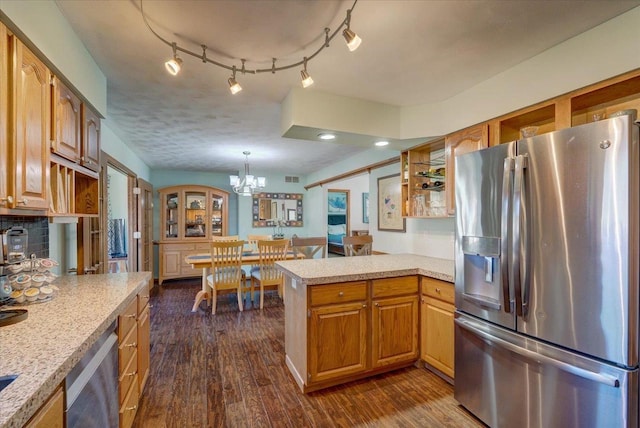 kitchen with appliances with stainless steel finishes, pendant lighting, dark hardwood / wood-style flooring, a notable chandelier, and kitchen peninsula