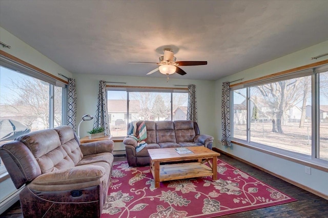 living room with ceiling fan, wood-type flooring, a baseboard heating unit, and a wealth of natural light