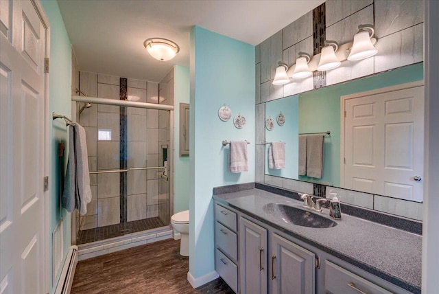 bathroom featuring toilet, baseboard heating, vanity, a shower with door, and hardwood / wood-style floors