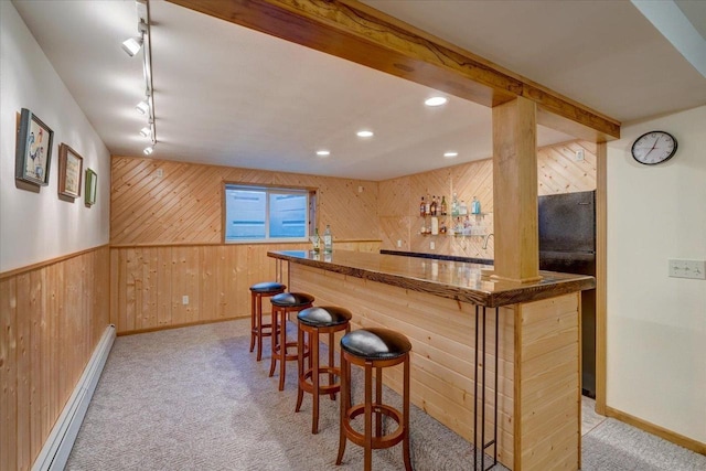 bar with baseboard heating, track lighting, wooden walls, light colored carpet, and beam ceiling