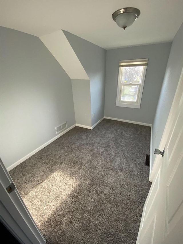 bonus room featuring vaulted ceiling and dark colored carpet