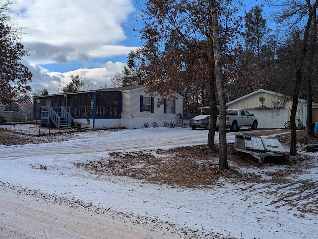 exterior space with a garage, a sunroom, and an outbuilding