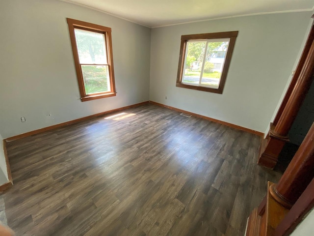 spare room with decorative columns, ornamental molding, and dark hardwood / wood-style flooring