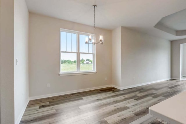 unfurnished dining area featuring a notable chandelier and hardwood / wood-style flooring