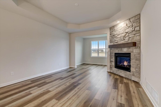 unfurnished living room with wood-type flooring, a fireplace, and a tray ceiling