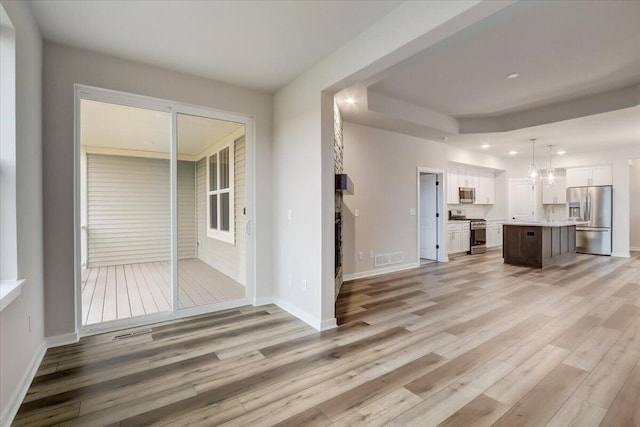 unfurnished living room featuring light hardwood / wood-style flooring and a notable chandelier