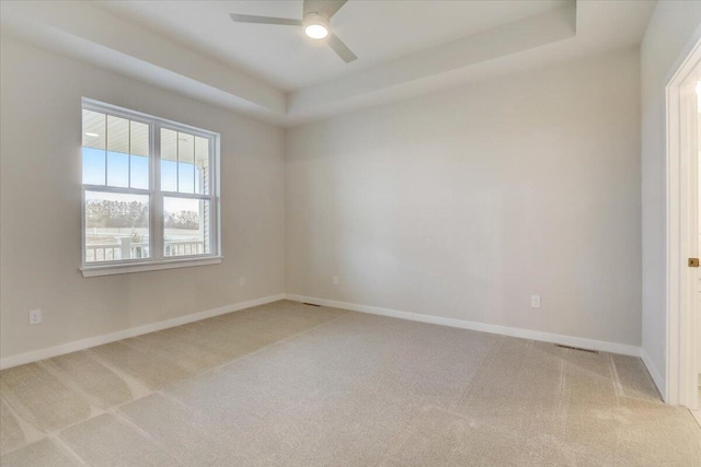 unfurnished room featuring carpet floors, a raised ceiling, and ceiling fan