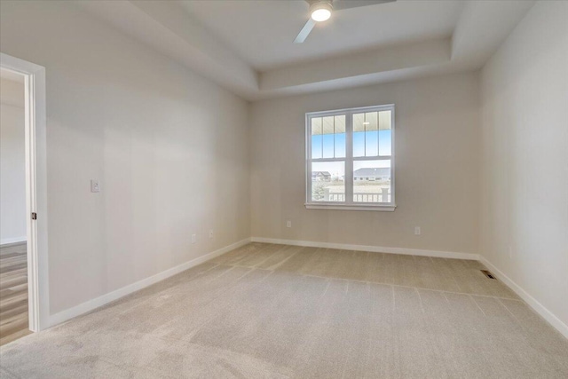 carpeted empty room featuring ceiling fan and a tray ceiling