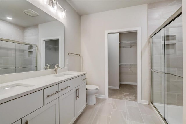 bathroom with tile patterned floors, vanity, toilet, and a shower with door