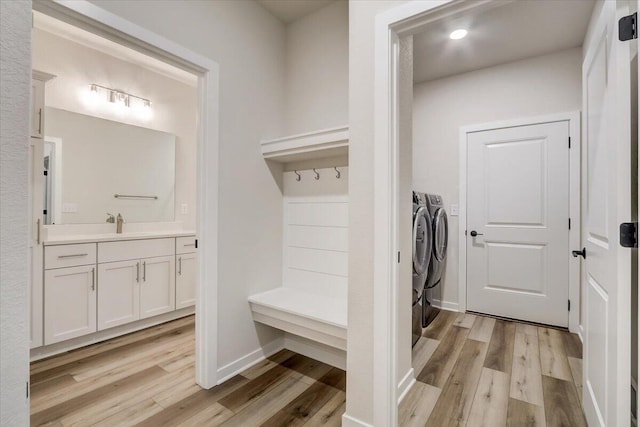 mudroom featuring sink, washer and dryer, and light wood-type flooring