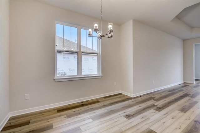 unfurnished dining area with hardwood / wood-style floors and a notable chandelier