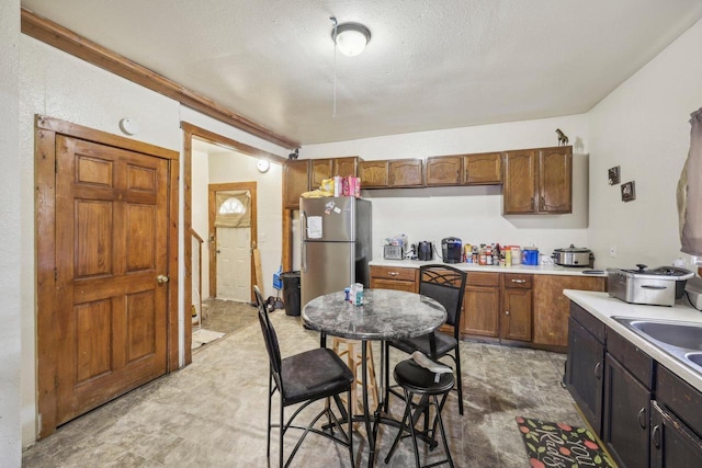 kitchen featuring stainless steel refrigerator, a kitchen bar, and a textured ceiling