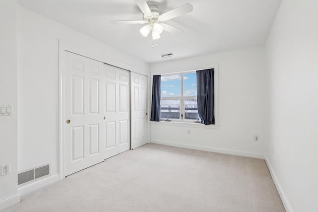 unfurnished bedroom featuring ceiling fan, light colored carpet, and a closet