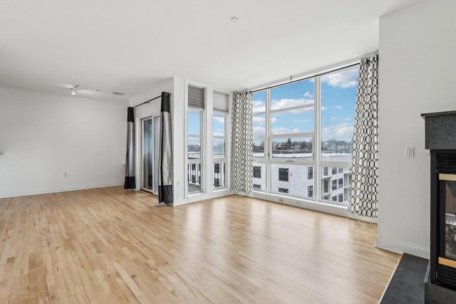 unfurnished living room featuring floor to ceiling windows and light wood-type flooring