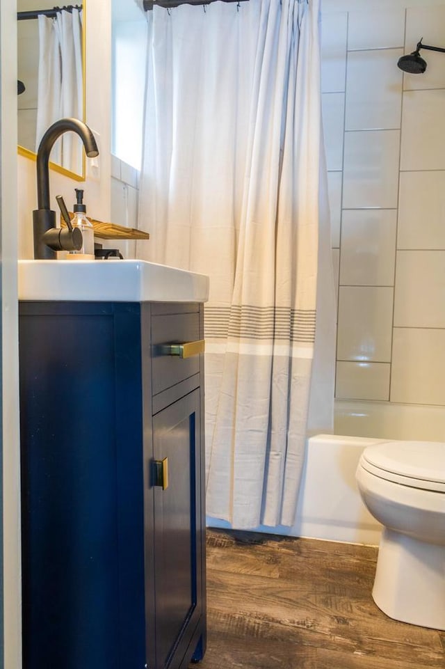 full bathroom with vanity, hardwood / wood-style floors, shower / tub combo, and toilet