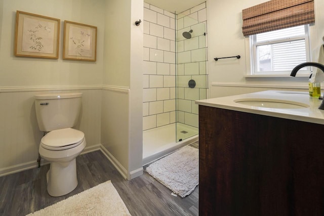 bathroom featuring vanity, tiled shower, hardwood / wood-style floors, and toilet