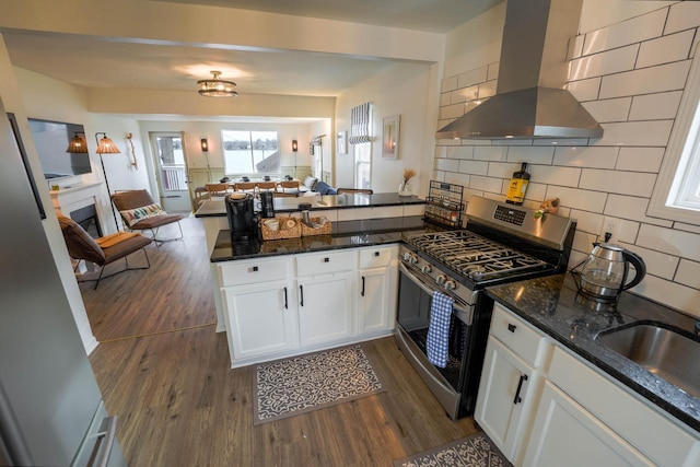 kitchen featuring gas range, island range hood, kitchen peninsula, and white cabinets