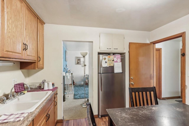 kitchen featuring sink, stainless steel fridge, and light hardwood / wood-style flooring