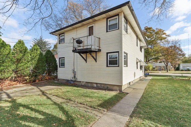 view of home's exterior with a balcony and a lawn