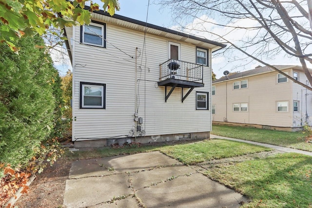 back of property featuring a balcony, a yard, and a patio