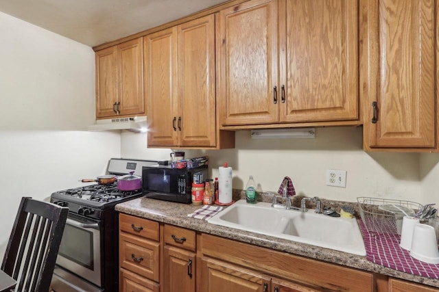 kitchen featuring stainless steel gas stove, sink, and dark stone countertops