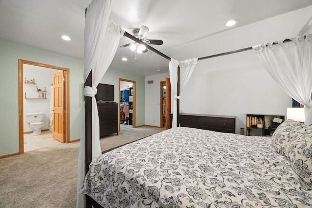 bedroom with ceiling fan, connected bathroom, light carpet, a spacious closet, and a closet