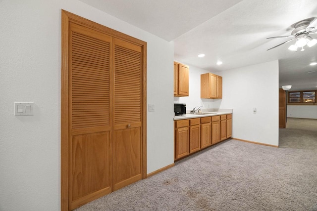 kitchen with sink, light carpet, and ceiling fan