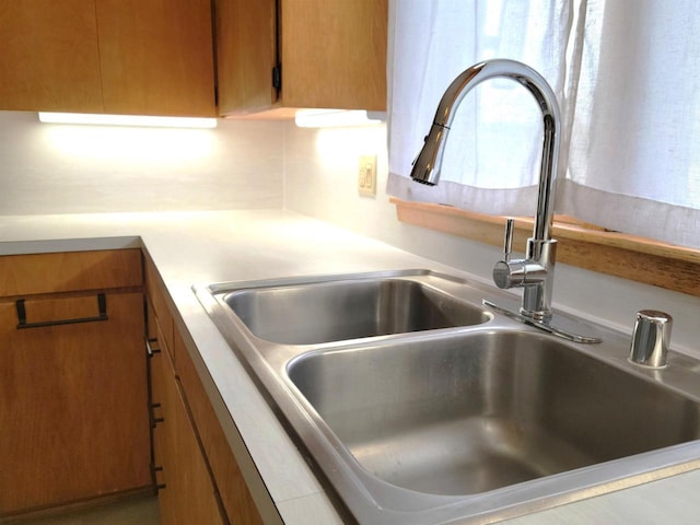 room details with brown cabinets, light countertops, and a sink