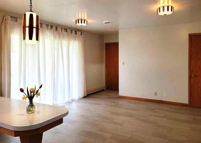 unfurnished dining area featuring light wood-type flooring and baseboards