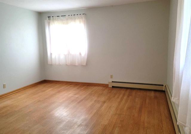 empty room with light wood finished floors, a baseboard radiator, and baseboards