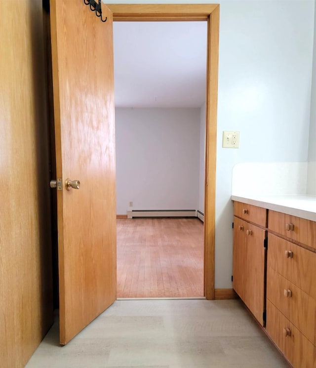 interior space with a baseboard heating unit, vanity, and wood finished floors