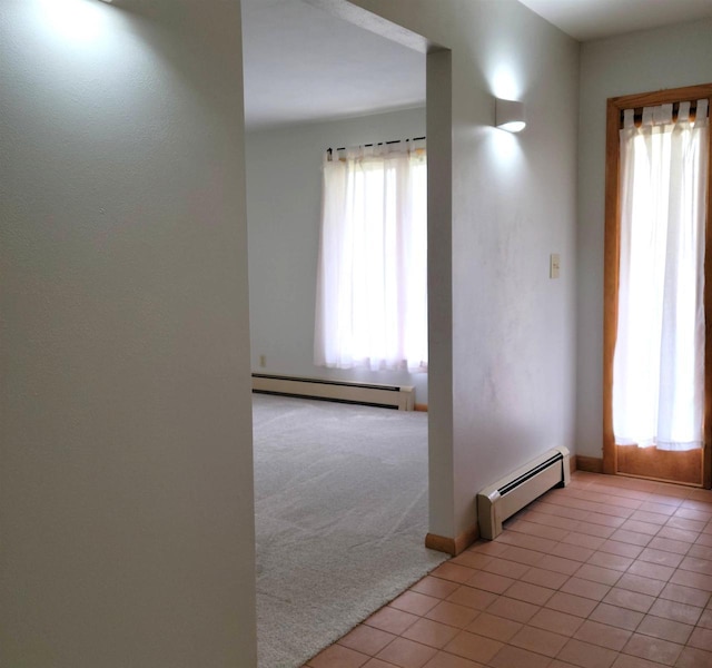 spare room featuring light tile patterned floors, a baseboard heating unit, and light colored carpet