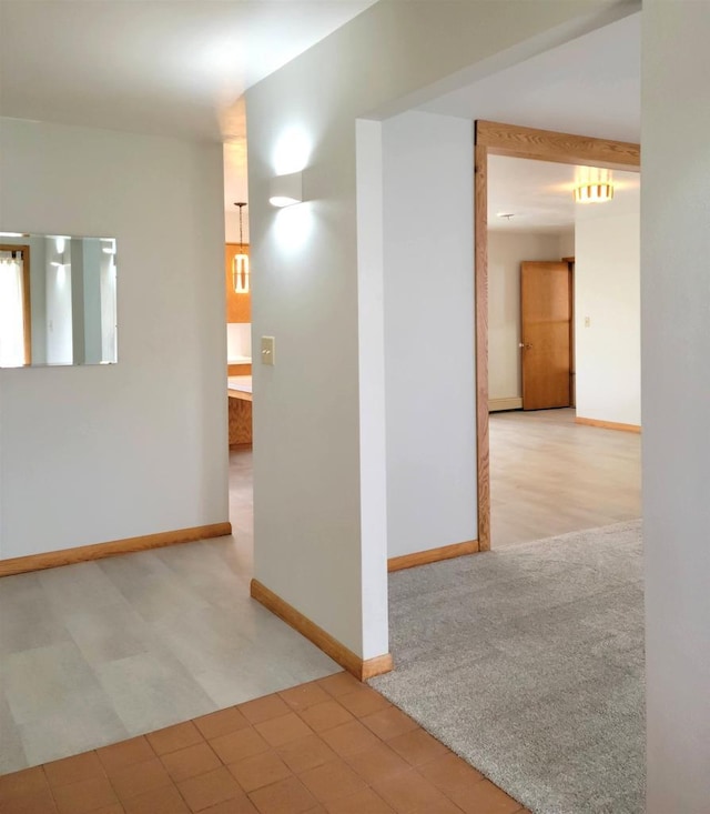 hallway featuring light carpet and baseboards