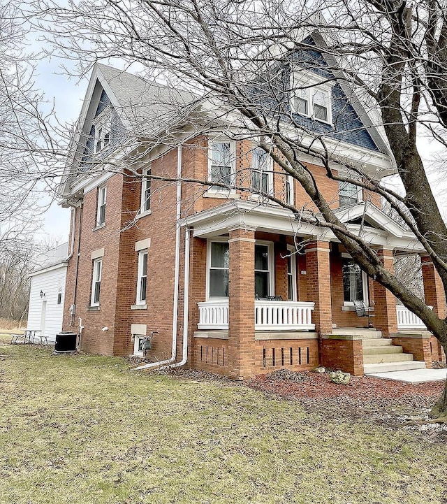 view of side of property with a porch, central AC unit, and a lawn