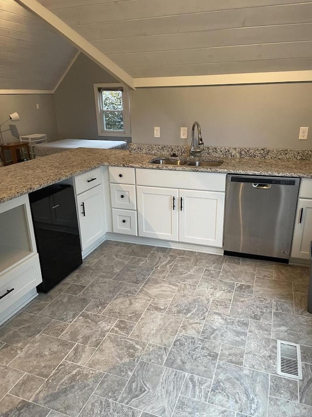 kitchen featuring lofted ceiling, sink, white cabinetry, light stone counters, and stainless steel dishwasher