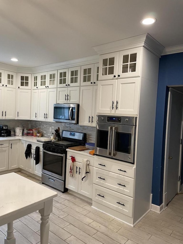 kitchen with tasteful backsplash, white cabinetry, appliances with stainless steel finishes, and ornamental molding