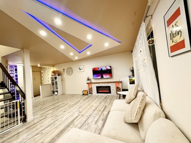 living room with a stone fireplace and light wood-type flooring