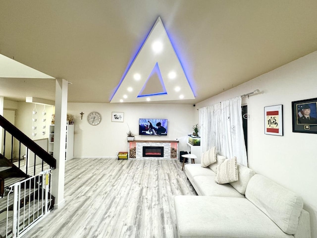 living room featuring a stone fireplace and light hardwood / wood-style flooring