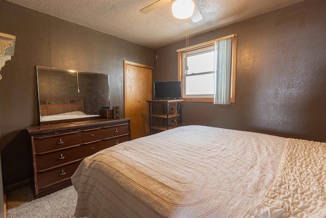 bedroom featuring light colored carpet, ceiling fan, a closet, and a textured ceiling