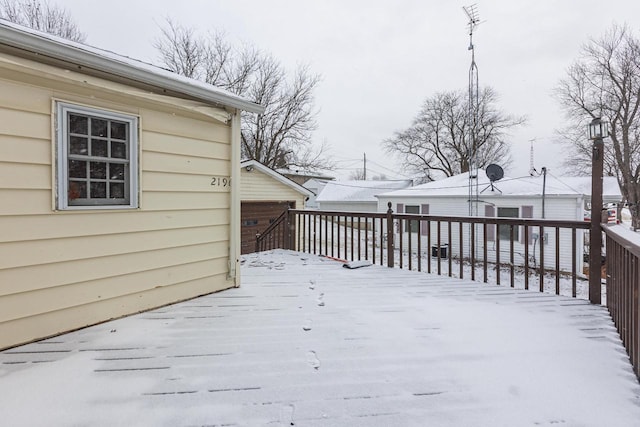 snow covered deck with a garage and an outbuilding