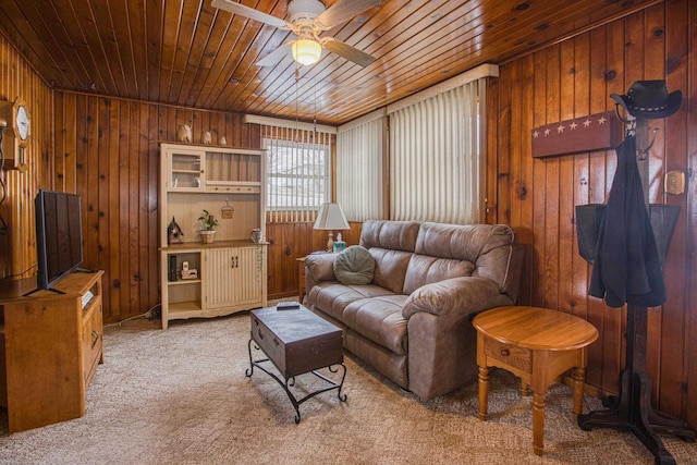 carpeted living room featuring wooden ceiling, ceiling fan, and wood walls